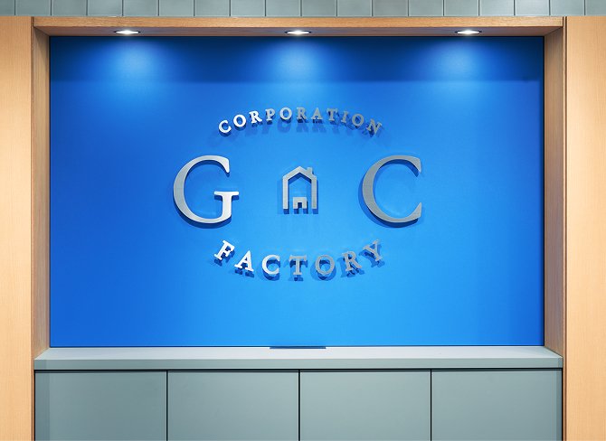 青い壁にG.Cファクトリーのロゴが掲載されたエントランス